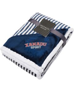 An angled view of a navy and white zig zag striped blanket folded up. In the corner there is a navy triangle of material with an embroidered logo on it 