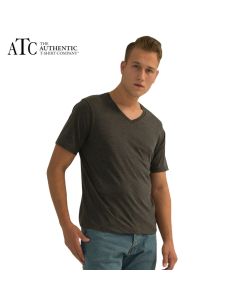 A charcoal heather coloured ring spun V-neck tee being worn by a short haired man with one hand in his pocket standing in front or a grey wall