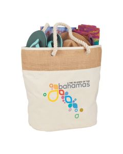 A promotional jute and cotton canvas tote with rope handles. The front has a printed logo and the bag is filled with goods.