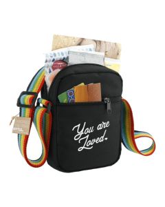 A black recycled crossbody tote with a rainbow strap. There is a white custom logo on the front and the bag is filled.