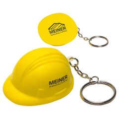 Two yellow coloured hard hat shaped stress relievers with silver coloured metal keychains and split ring attachments. The nearest hat is upright and has a black logo on the side. The hat behind it is turned to show the base with a black logo