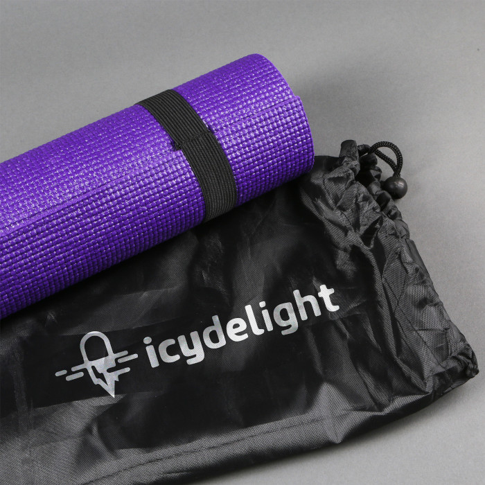 An angled view of a purple yoga mat and black storage bag. The bag has a white logo on and both items are on top of a grey floor.