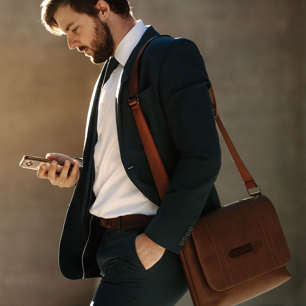 Business man carries branded bag while checking his phone