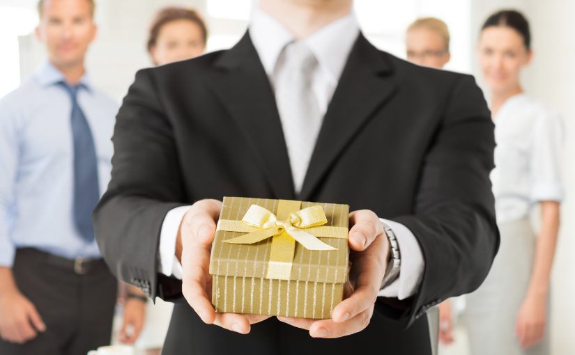 Business man hands over wrapped gift box to client