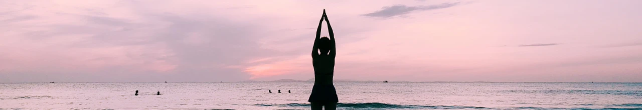 photo of a woman doing yoga at the beach during sunset